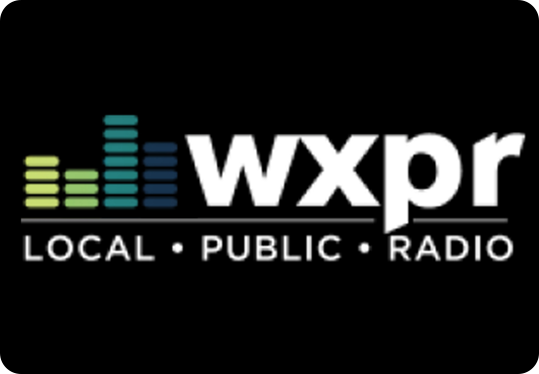 WXPR logo on a black background, featuring colored vertical bars resembling an equalizer, and the words wxpr LOCAL • PUBLIC • RADIO in white text.
